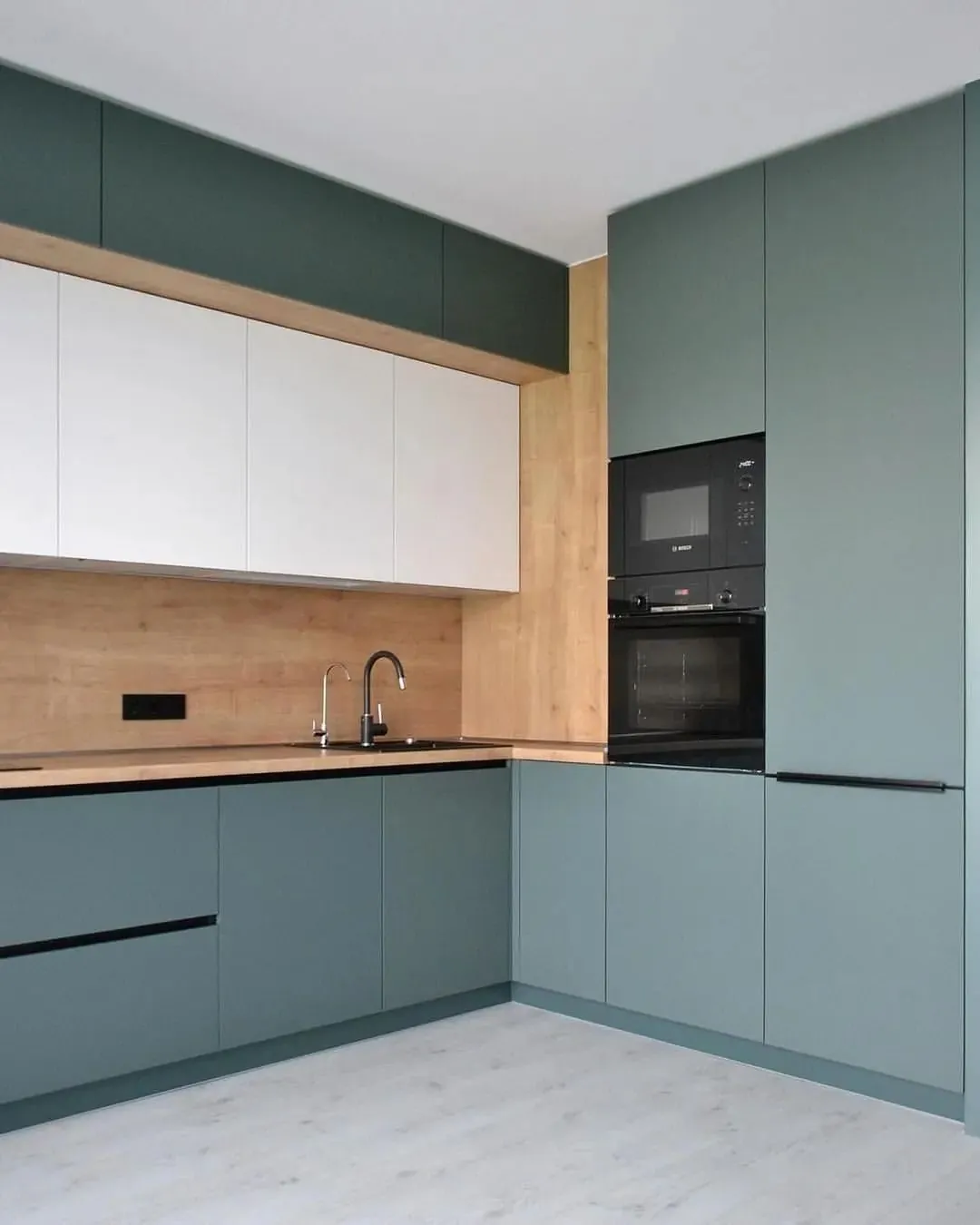 Integrated ovens set into sage green tall cabinets